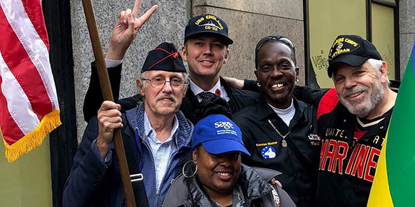 Veterans - Five Veterans holding American flag and Pride flag. Photo Credit SAGE